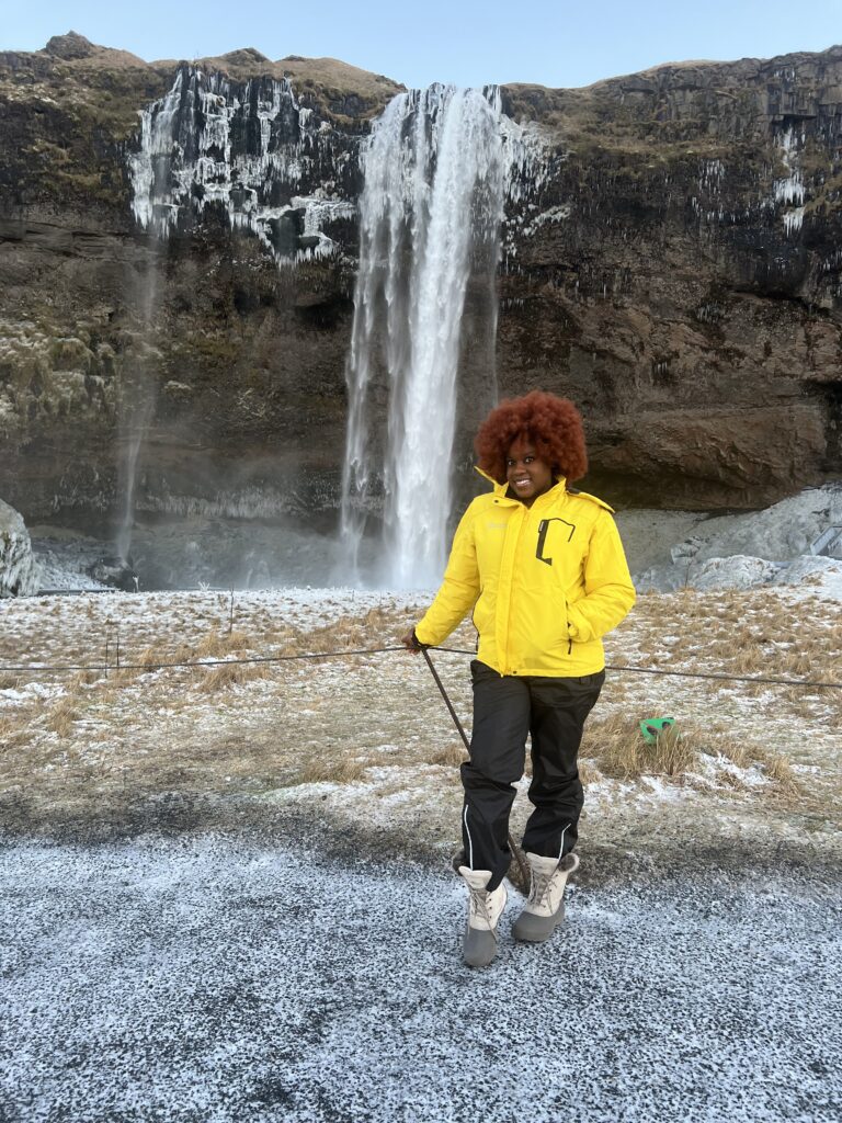 Black woman with ginger afro in front of Seljalandsfoss Waterfakk