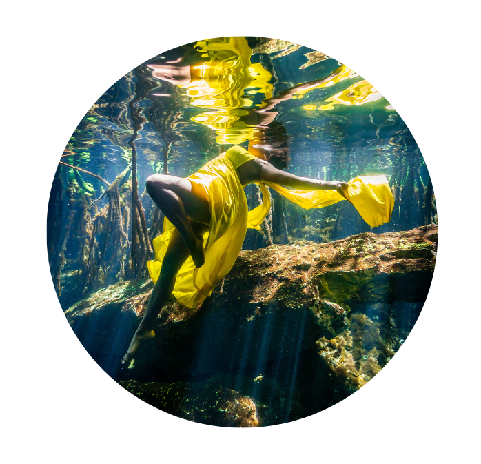 black woman in yellow dress floating in cenotes