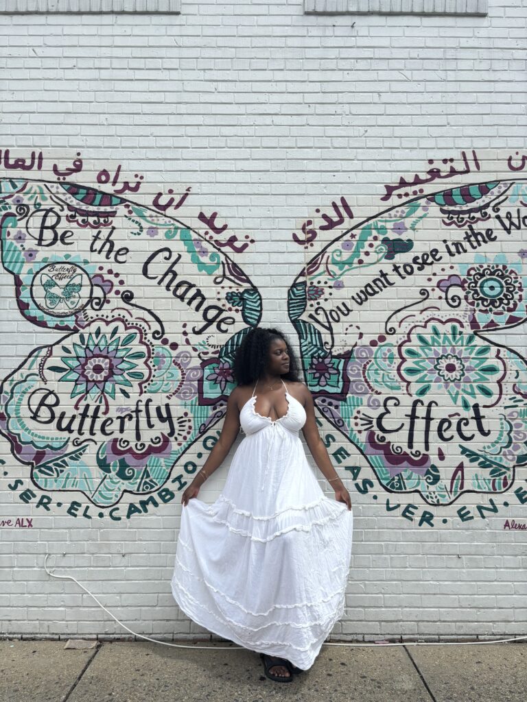 Black woman standing in front of a butterfly mural in Old Town Alexandria