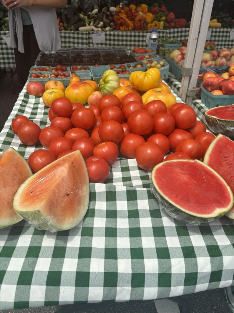 watermelon, tomatoes, and other fruits at a farmers market