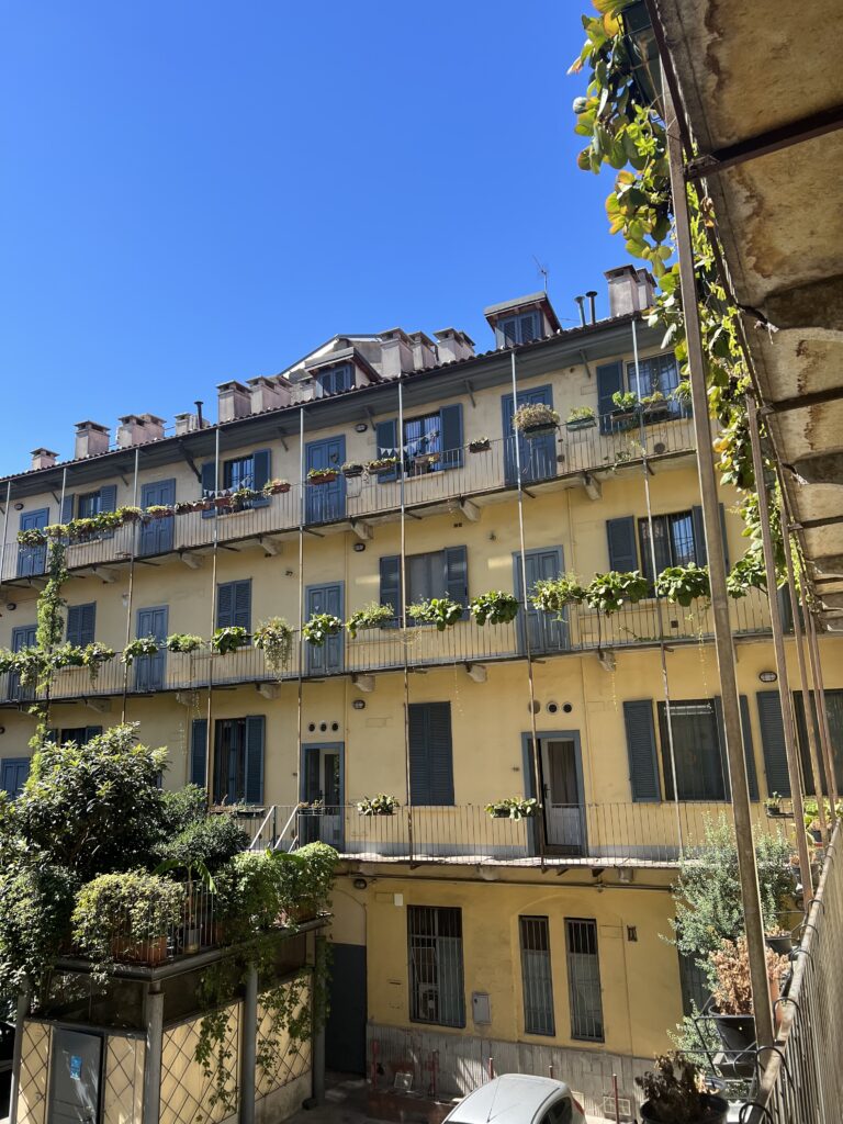 yellow 4 store hotel with green ivy growing on the terrace