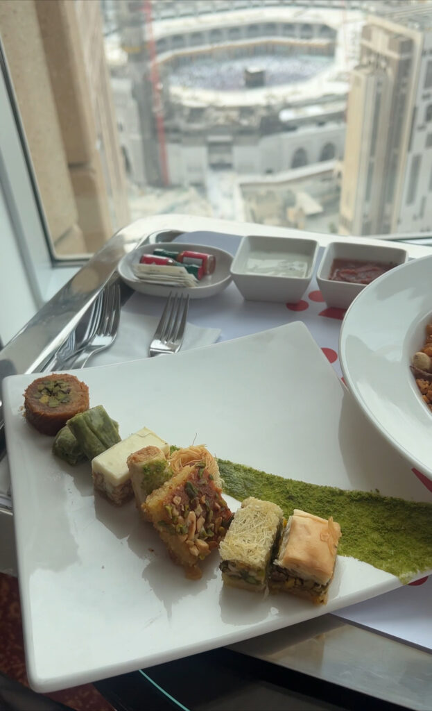 a plate of middle eastern desserts in front of a window with a view of the Kaba