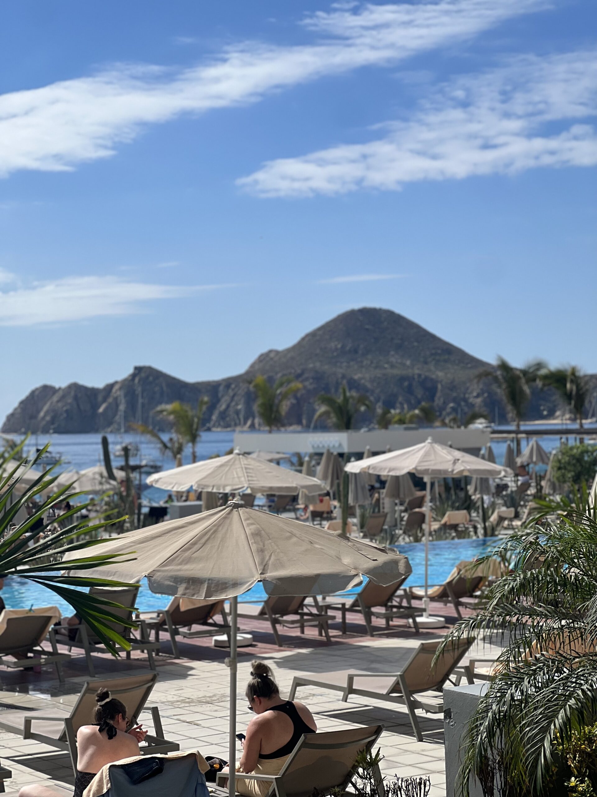 view of pool, pool chairs, and the Arch of Cabo at RIU Baja California