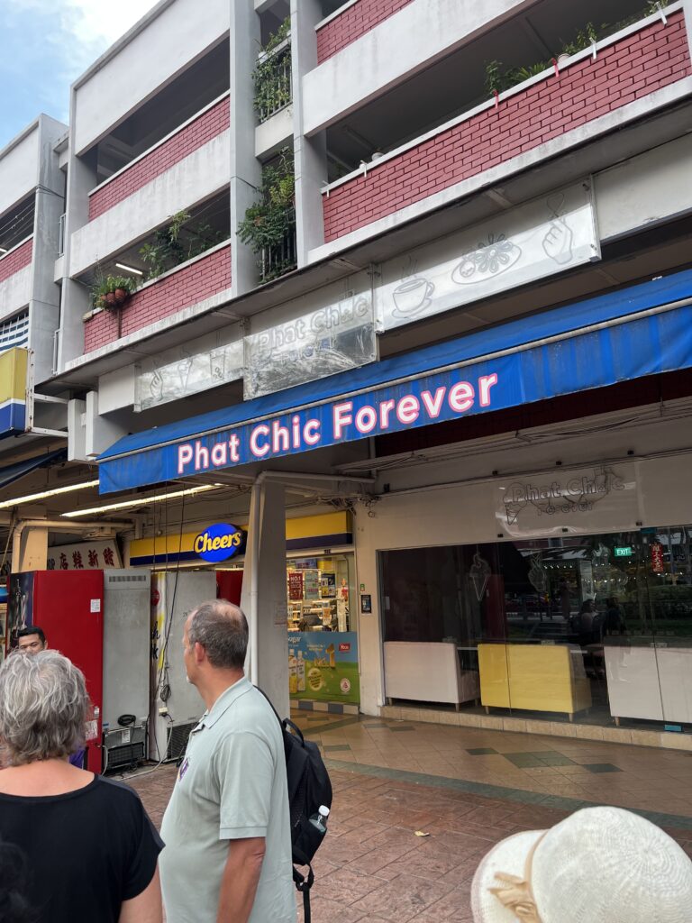 tourists standing in front of a store that says "Phat Chic Forever" during the Free Singapore layover