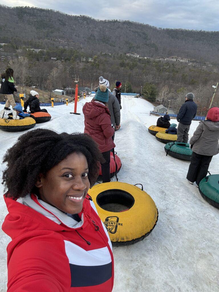 a Black woman with an afro smiling on top of Massanutten Resort before going snow tubing