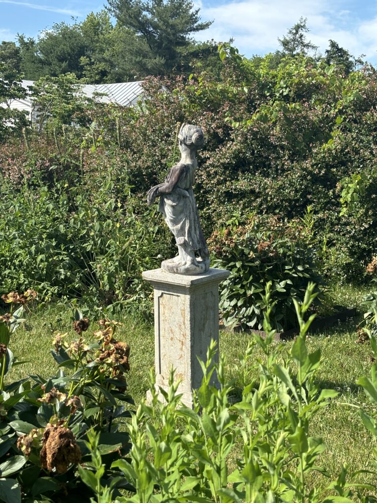 a statue of a young girl in a lush garden