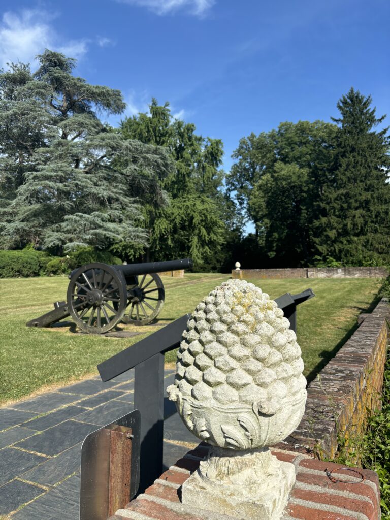 a pineapple shaped stone entrance figure and an old black cannon in the background