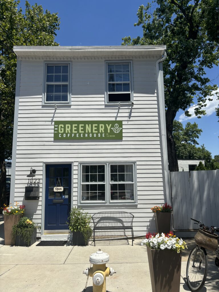 a 2 story white house with a sign that says "The Greenery Coffeehouse"