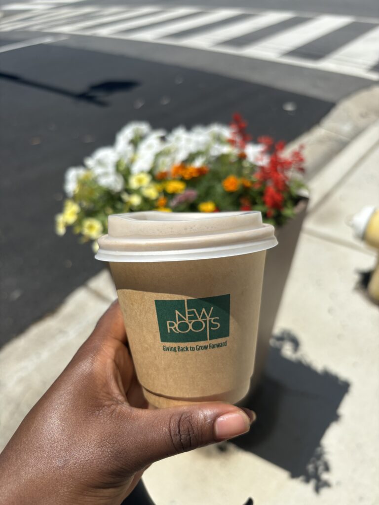 a Black woman's hand holding a disposable coffee cup