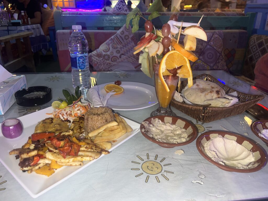 a table fille dwith Egyptian food and an Egyptian drink with lots of oranges, grapes, apples, and mangos on sticks