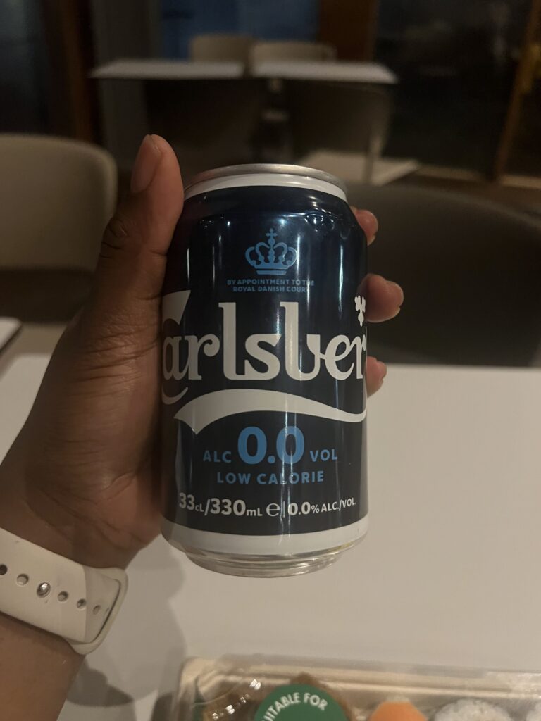 a Black woman holding a blue can of non-alcoholic beer