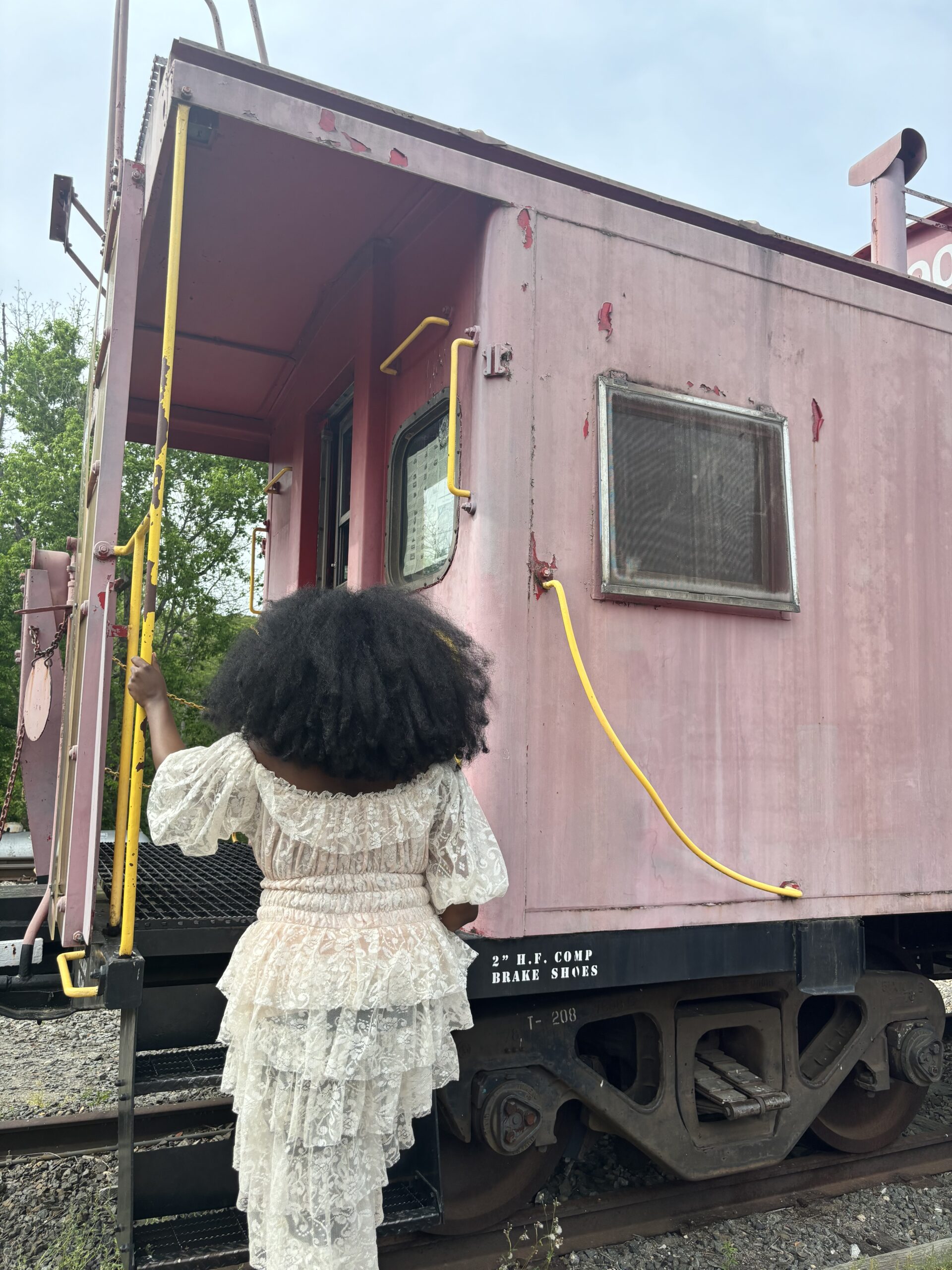 Black woman with large afro getting into a historic train at Devereux Station in Clifton