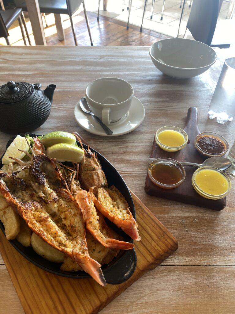 a restaurant in Cape Town a table with lobster and potatoes, and a green ceramic tea pot