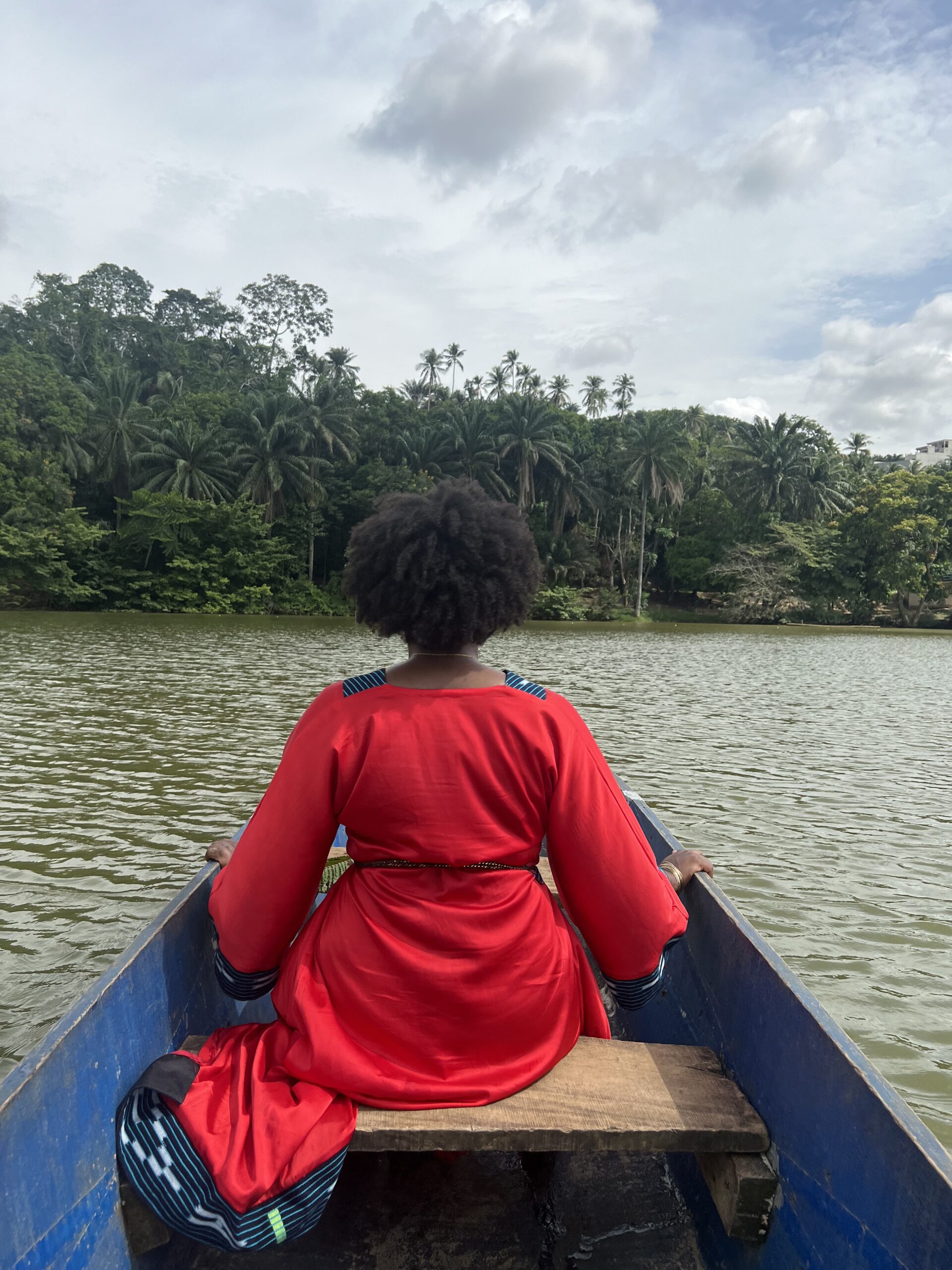 a Black woman in a red dress sitting in a canoe in Bini Lagune