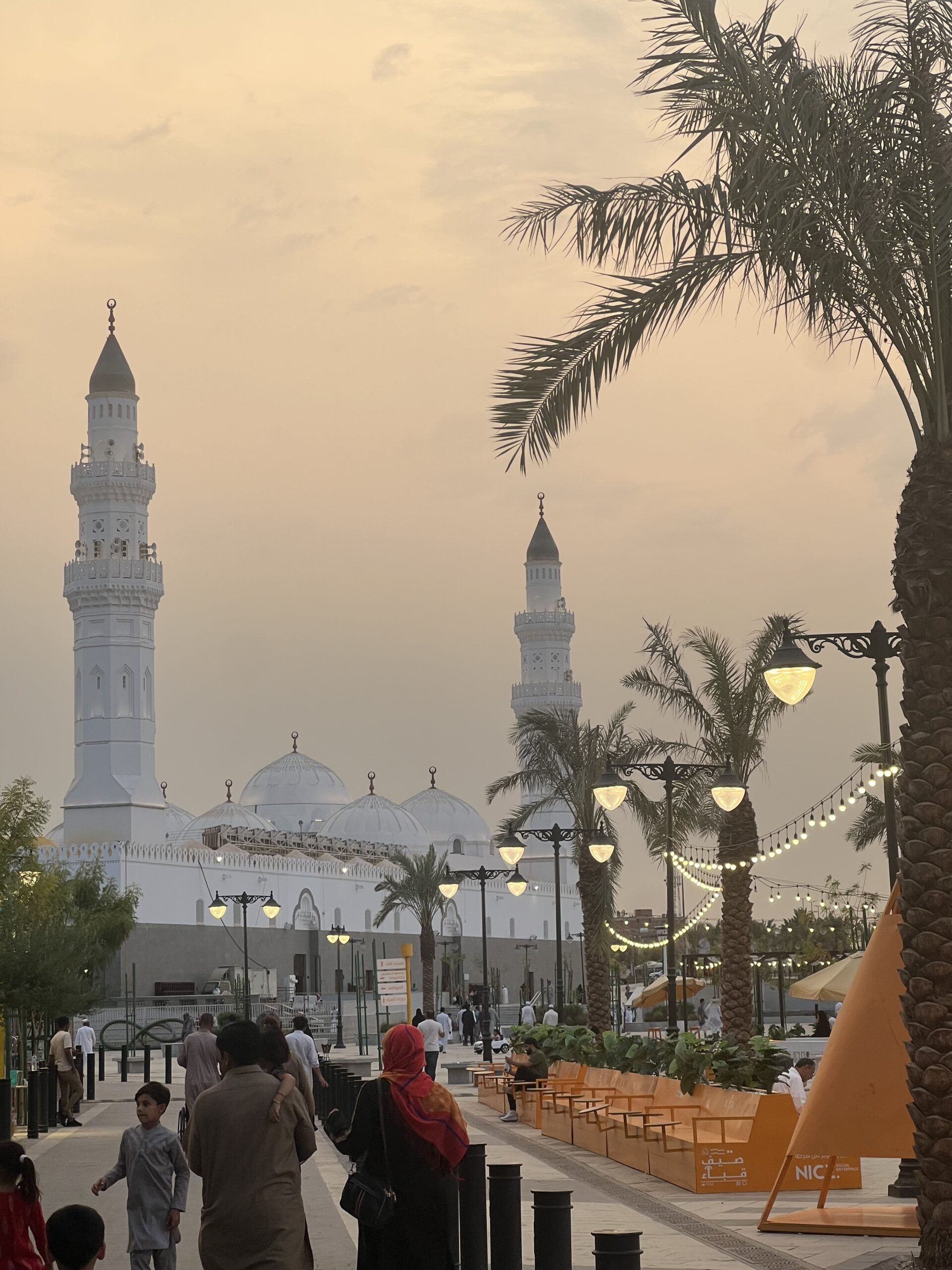 masjid al quba at dusk with people walking in front of it