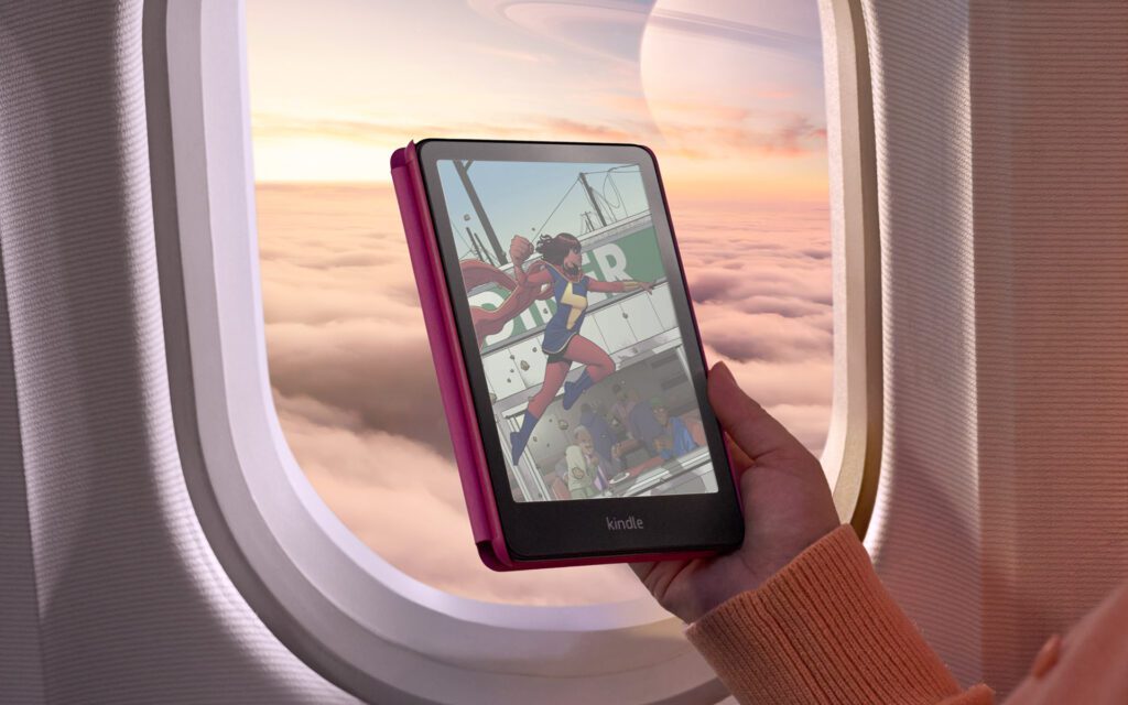 a woman holding a colorsoft kindle in front of an airport window