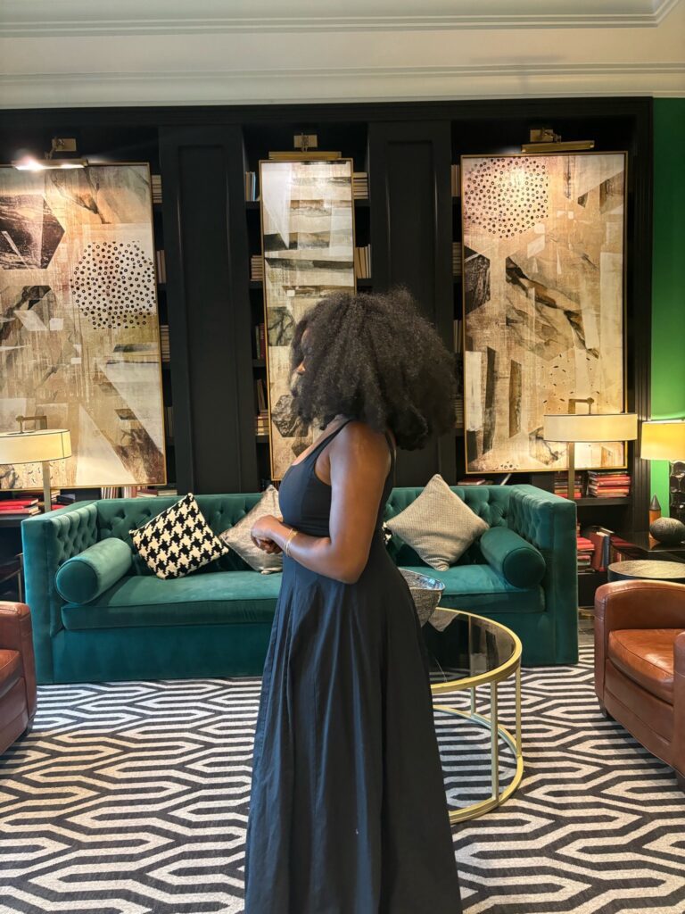 Black woman in Black dress in a luxury room with a gold couch and gorgeous pieces of art