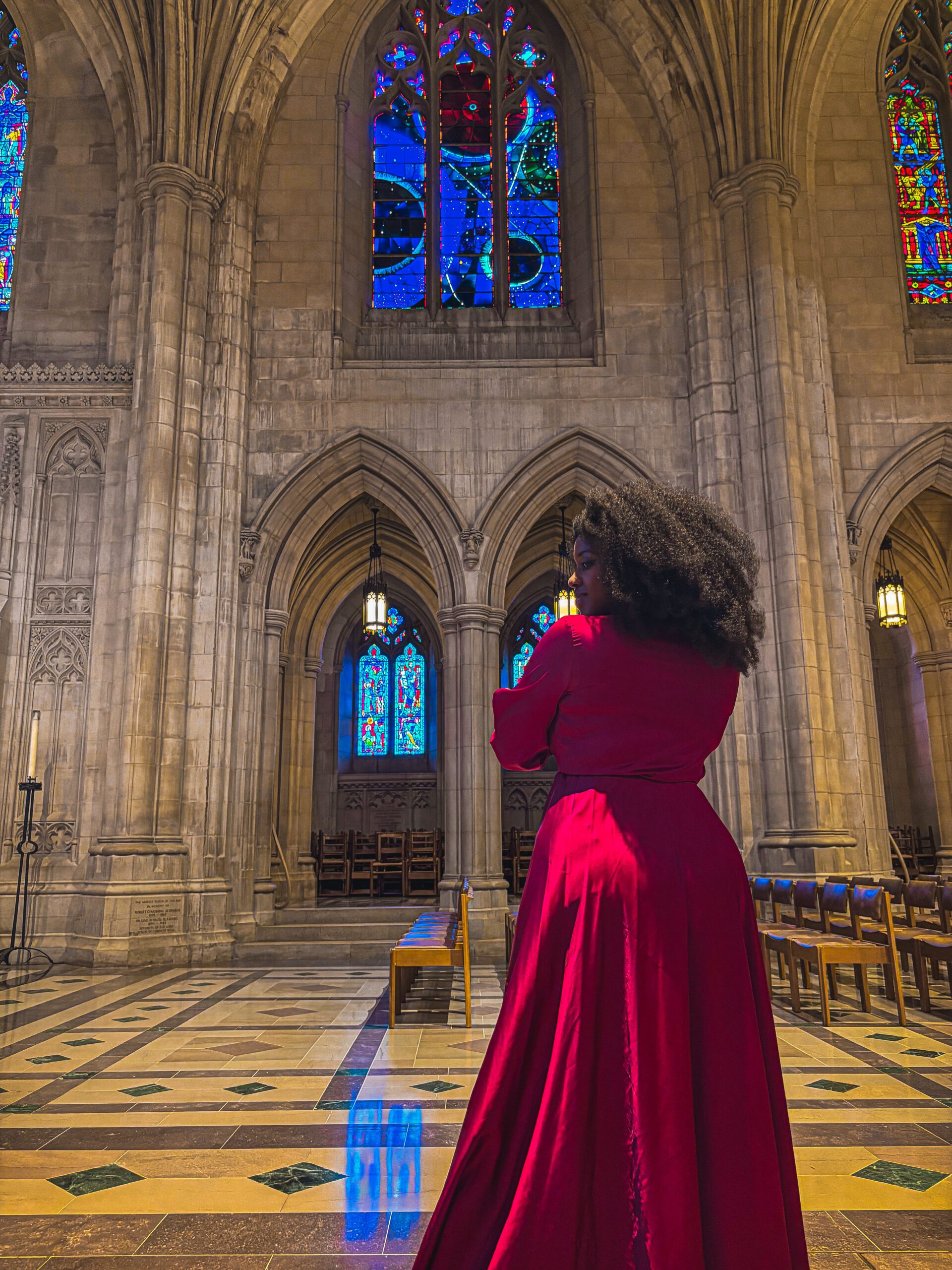 Black woman with large afro in pink long dress inside the Washington National Cathedral