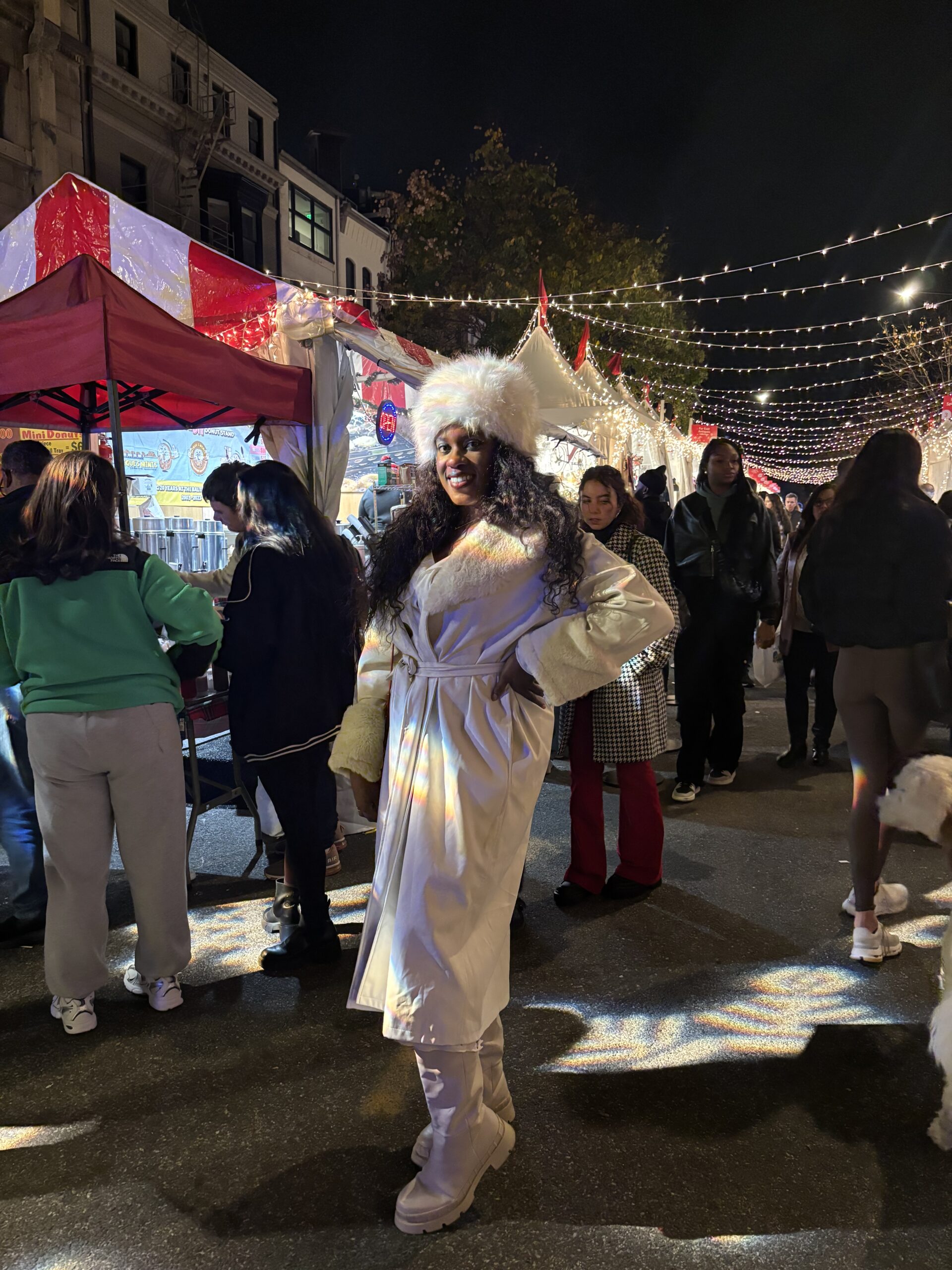 a Black woman in a white coat and white fluffy hat in a Christmas Market in Dupont Circle DC