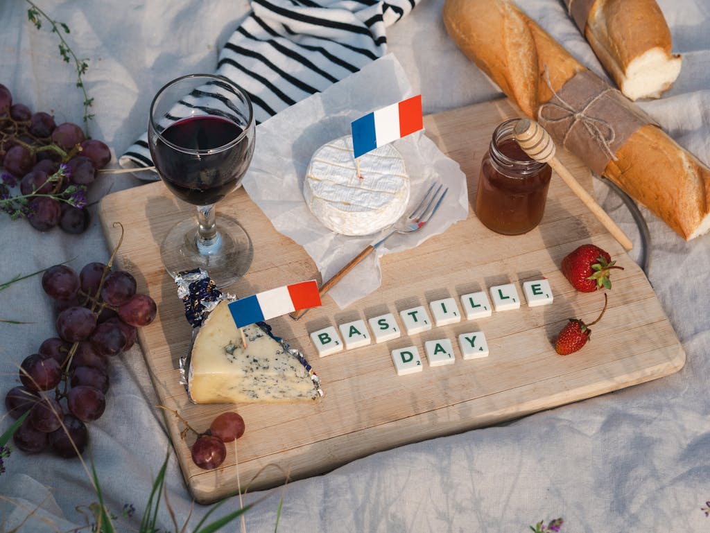 Celebrate Bastille Day with French wine, cheese, and traditional baguettes in a picturesque picnic setting.