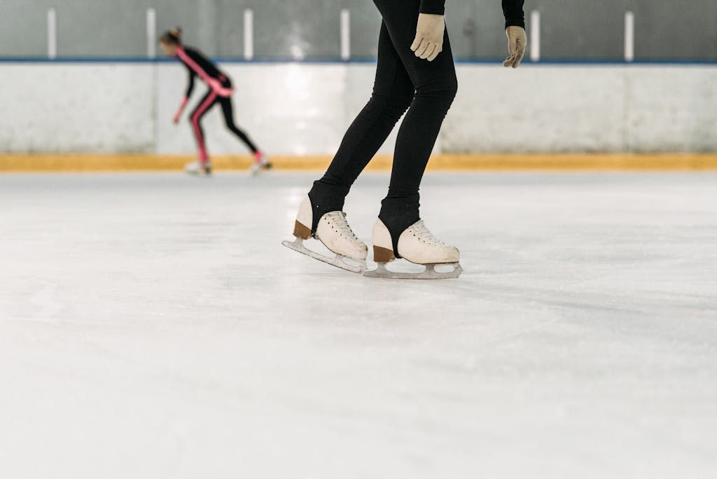 Two figure skaters training on an indoor ice rink, focusing on skill and balance.