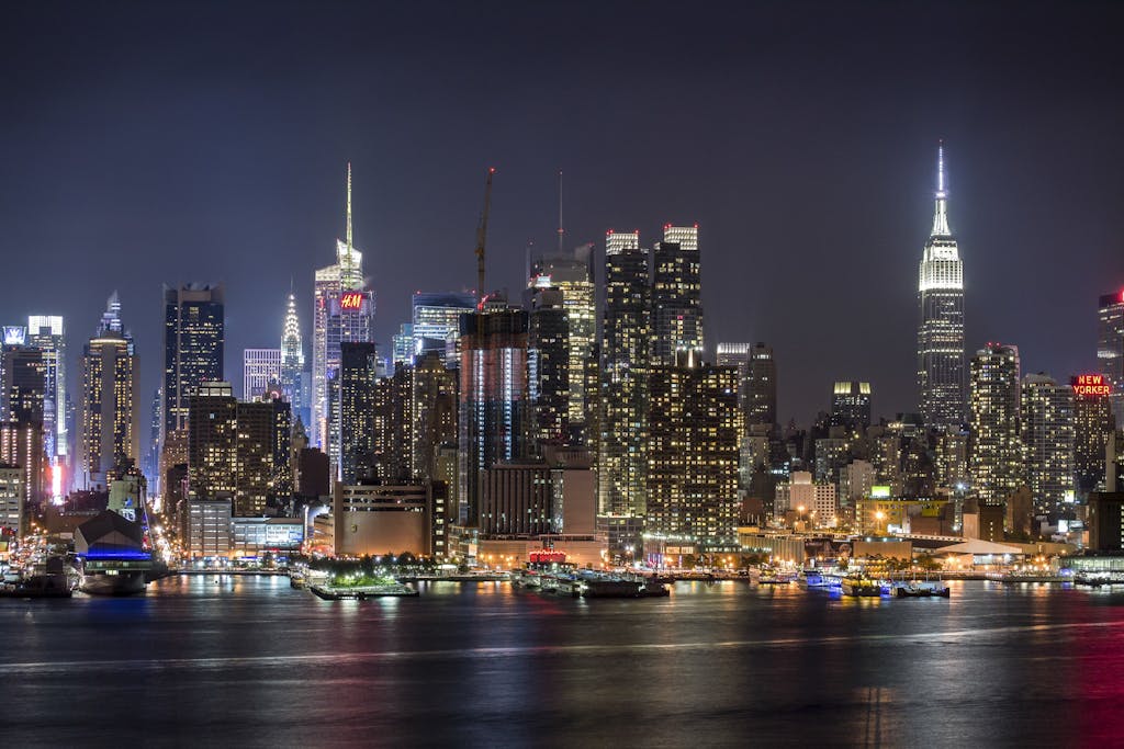 Stunning view of the illuminated New York City skyline reflecting on the Hudson River at night.