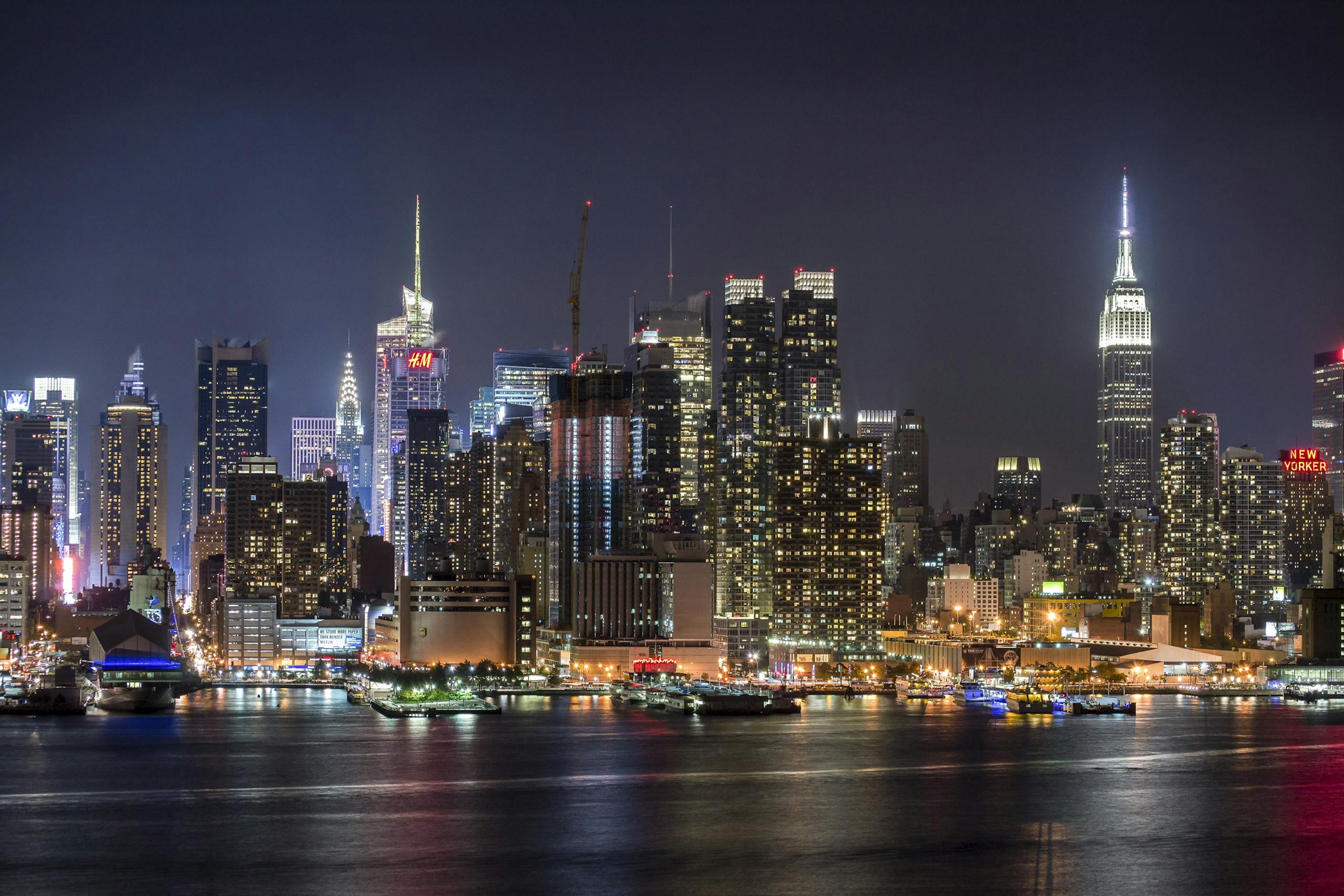 Stunning view of the illuminated New York City skyline reflecting on the Hudson River at night.