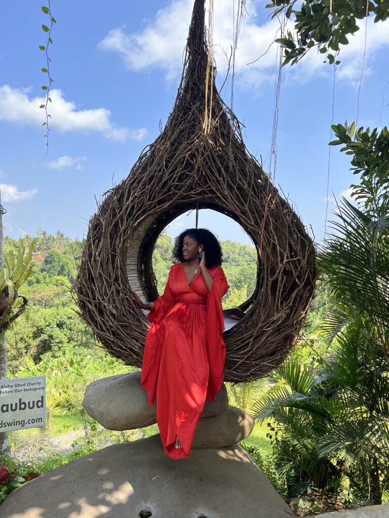 a Black woman in a red dress on a large bird nest 